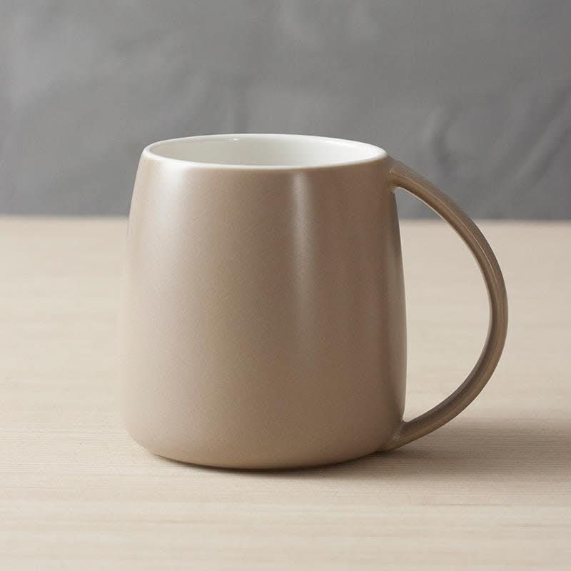 Nordic Ceramic Mug in taupe, minimalist Japanese design, on a light wood surface.