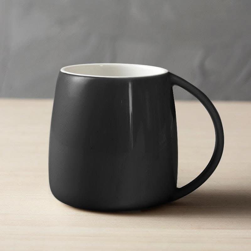 Matte black Nordic ceramic mug with white interior on a wooden surface, Japanese, Scandinavian, minimalist design.