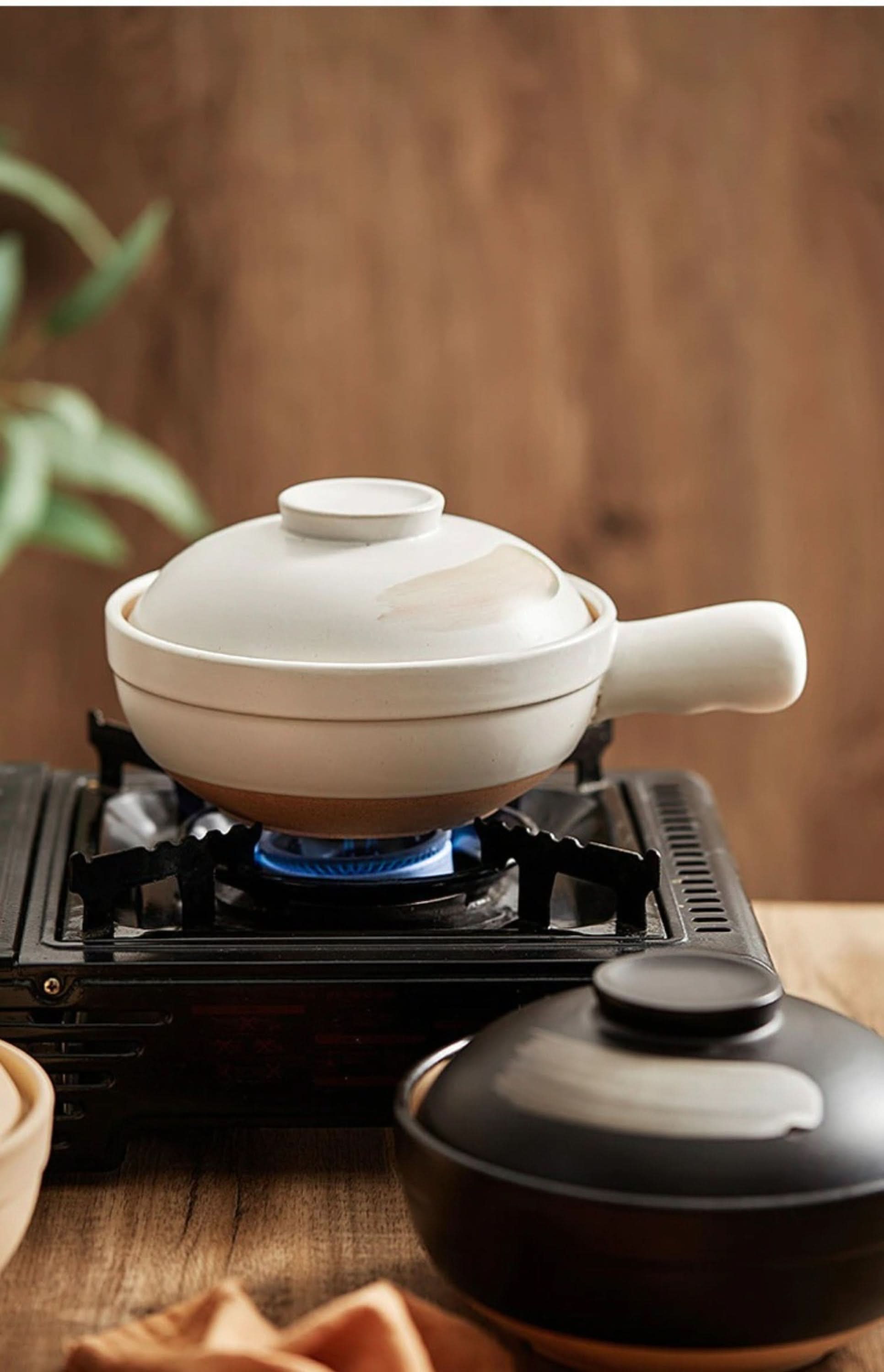 Rustic unglazed stoneware baking plate on a gas burner, kitchen tableware
