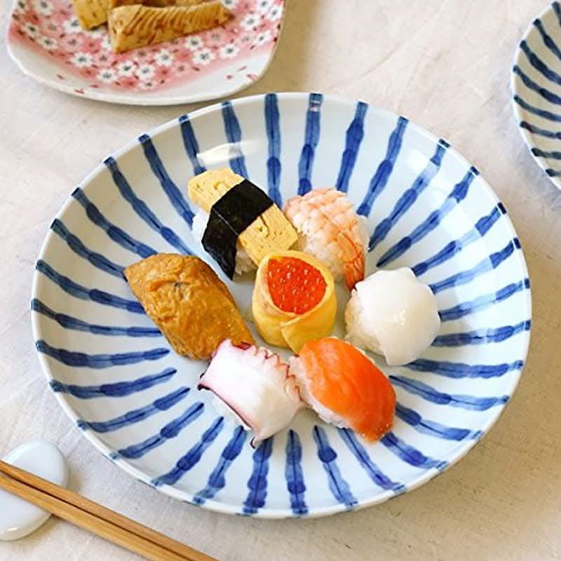 Ceramic Japanese irregular dinnerware with blue stripes holds assorted sushi.