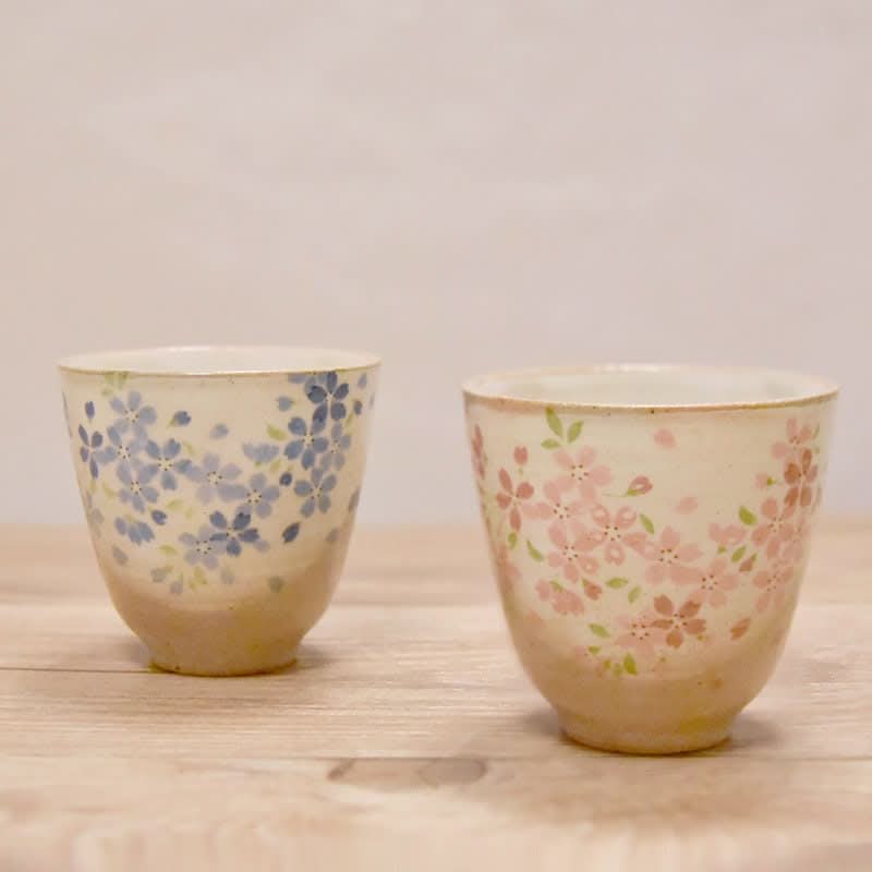 Japan Imported Stoneware Tea Cup Mugs with cherry blossoms, set of 2, on wood.