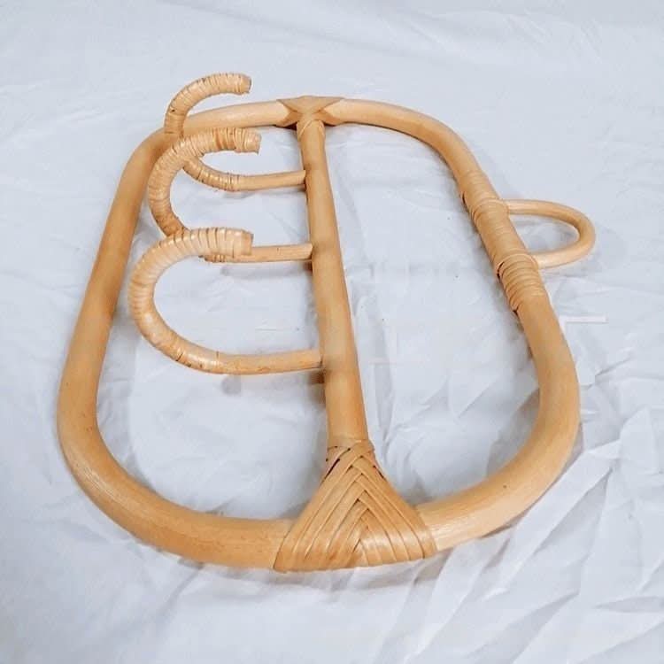 Natural rattan wall hanging hook and coat hangers with woven accents on white background.