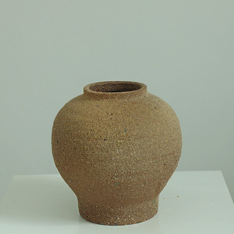 Rustic, rounded vase; light brown; rough texture.