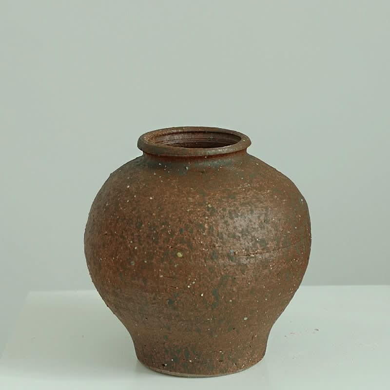 Rustic brown ceramic Wabi-Sabi vase with rounded shape and tight top on white surface.