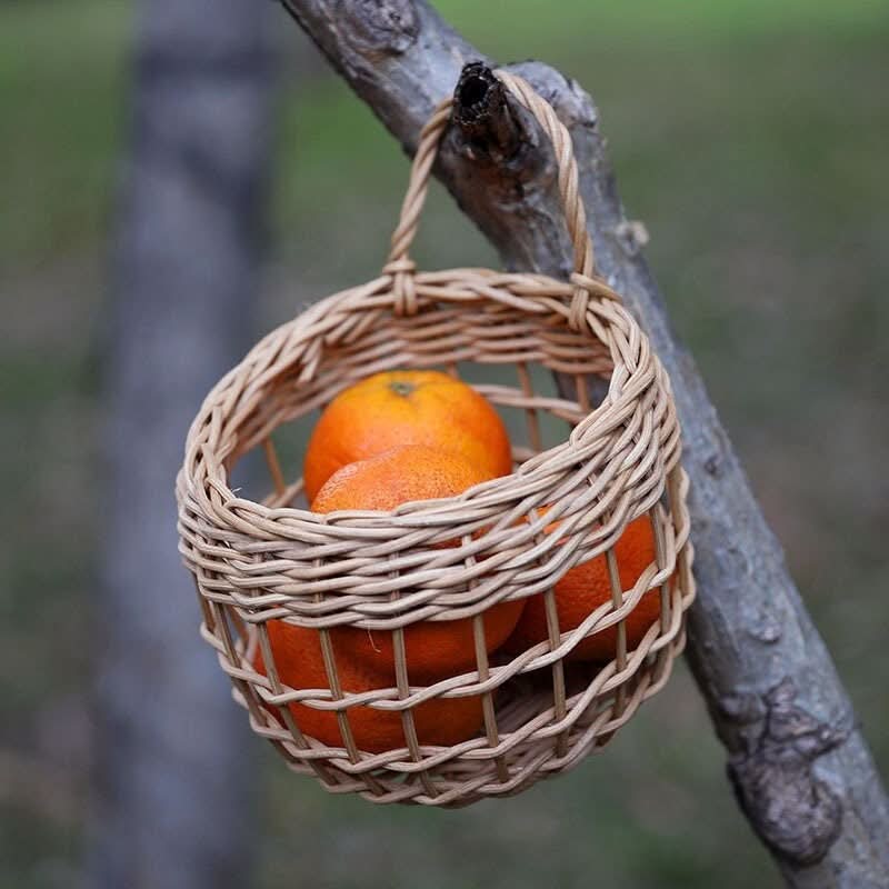 Wicker Kitchen Wall Hanging Basket with oranges, light brown woven material, hanging outdoors.
