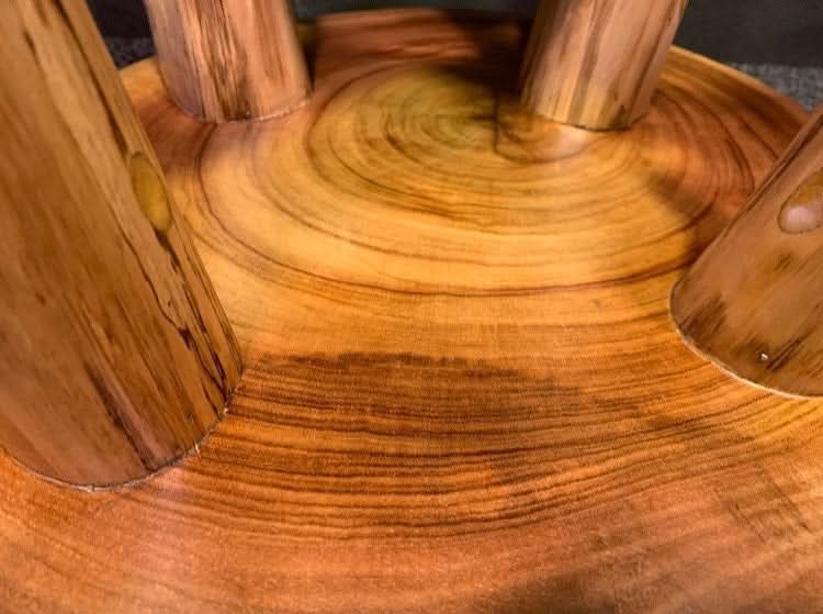 Solid wood tree ring stool with natural wood grain and legs.