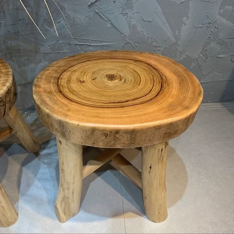 Solid Wood Tree Ring Stool with natural wood grain and rustic legs on a grey textured wall background.