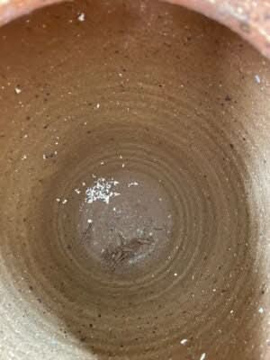 Close-up of antique ethnic vase interior, rustic brown ceramic with black tribal v patterns.