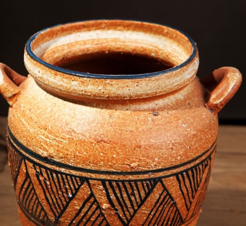 Rustic terracotta vase with black tribal patterns and handles. Home decor.