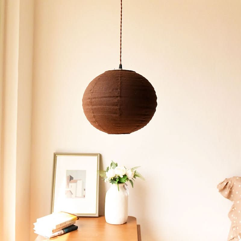 Brown linen ceiling shade, round shape, hanging above a table with decor.