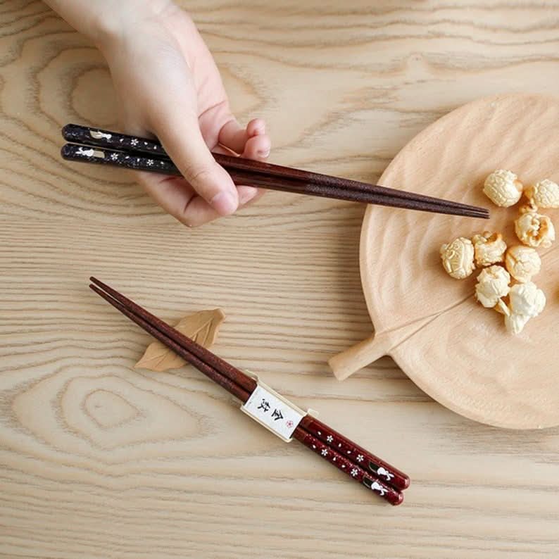 Imported Japanese Cherry Rabbit solid wood chopsticks on wood surface with popcorn.