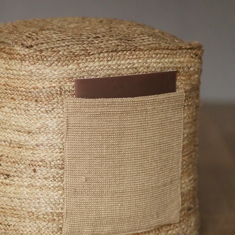 Close-up of Indian hand-woven natural jute ottoman with a brown leather pocket detail.