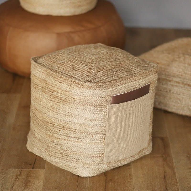 Indian hand-woven natural jute ottoman with leather accent on wooden floor.