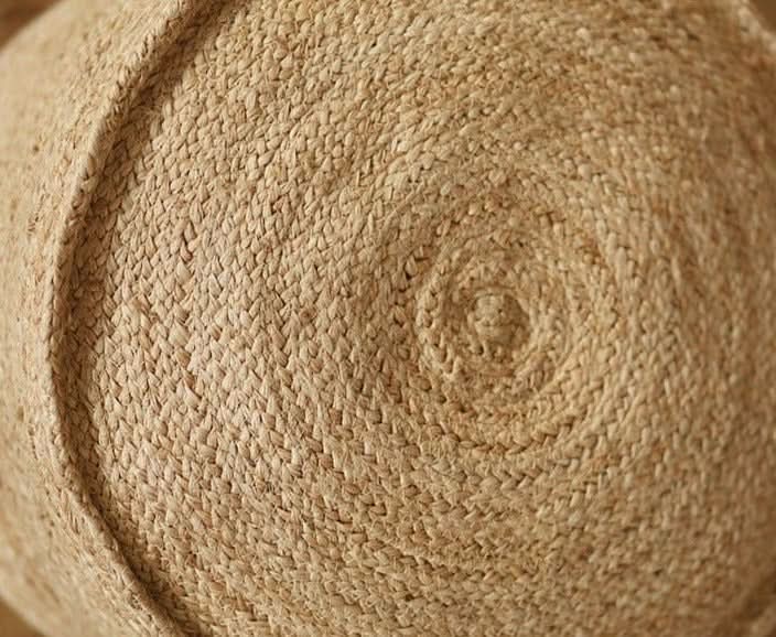 Close-up of Indian hand-woven natural jute ottoman with textured spiral pattern.