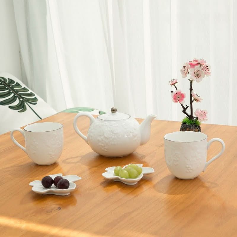 White Wabi-Sabi tea set with grape engraving, includes teapot & cups, on wooden table.