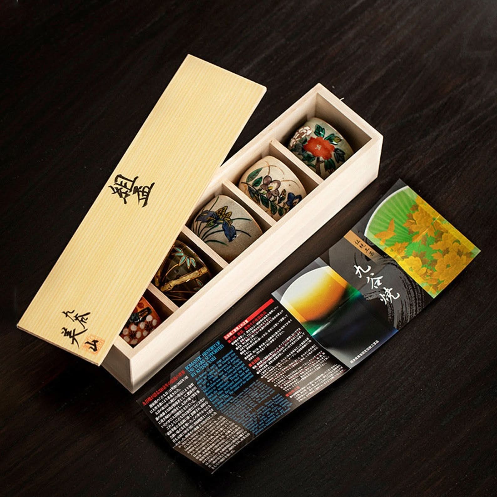 Set of Japanese ceramic tea cups with floral designs in a wooden box.