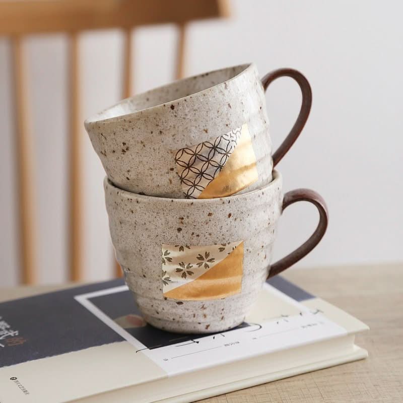 Japan imported foil mugs, a pair of speckled ceramic cups with gold accents.