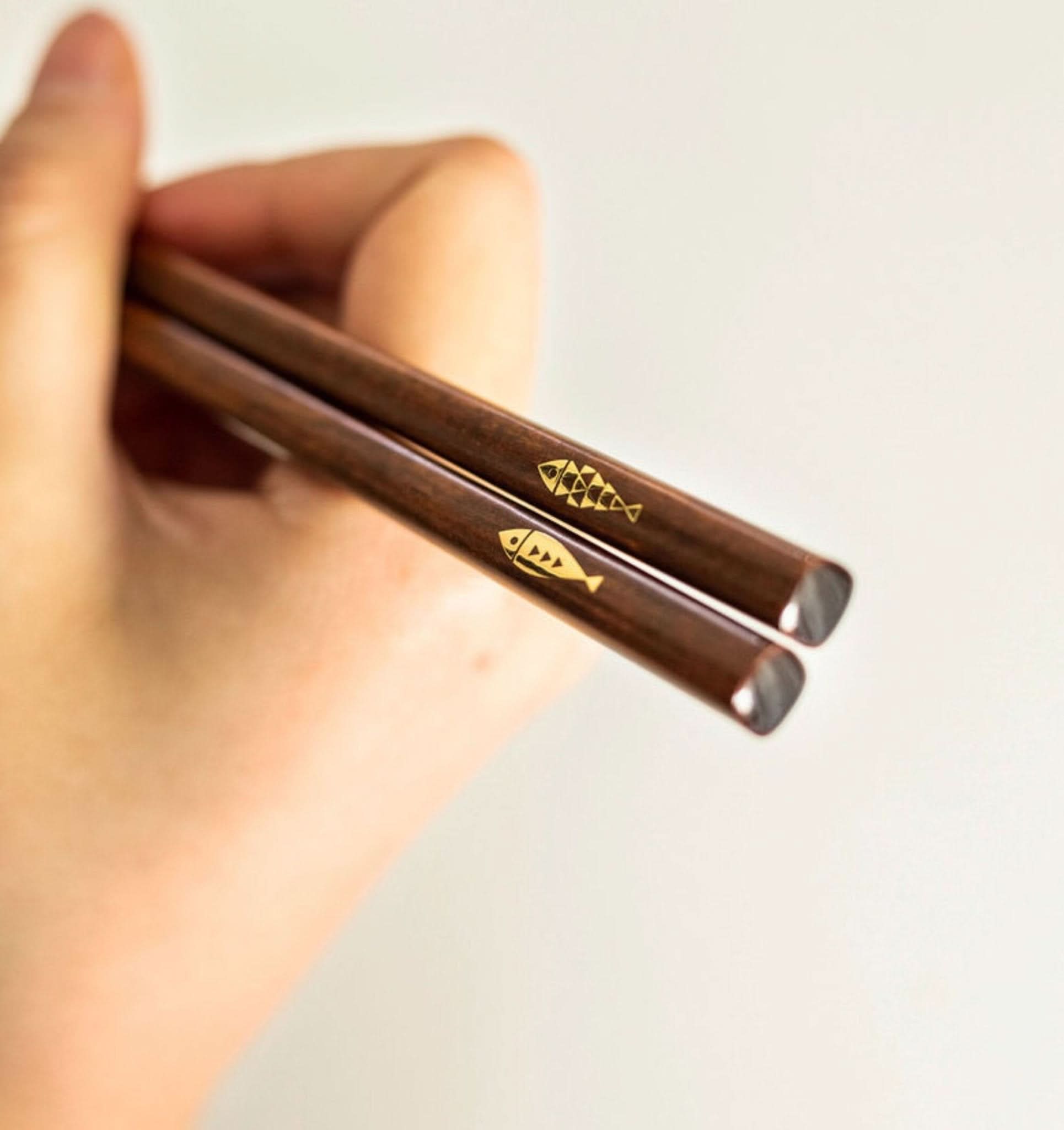 Japan Imported Handmade Wooden Chopsticks with cute gold fish design, held by hand.