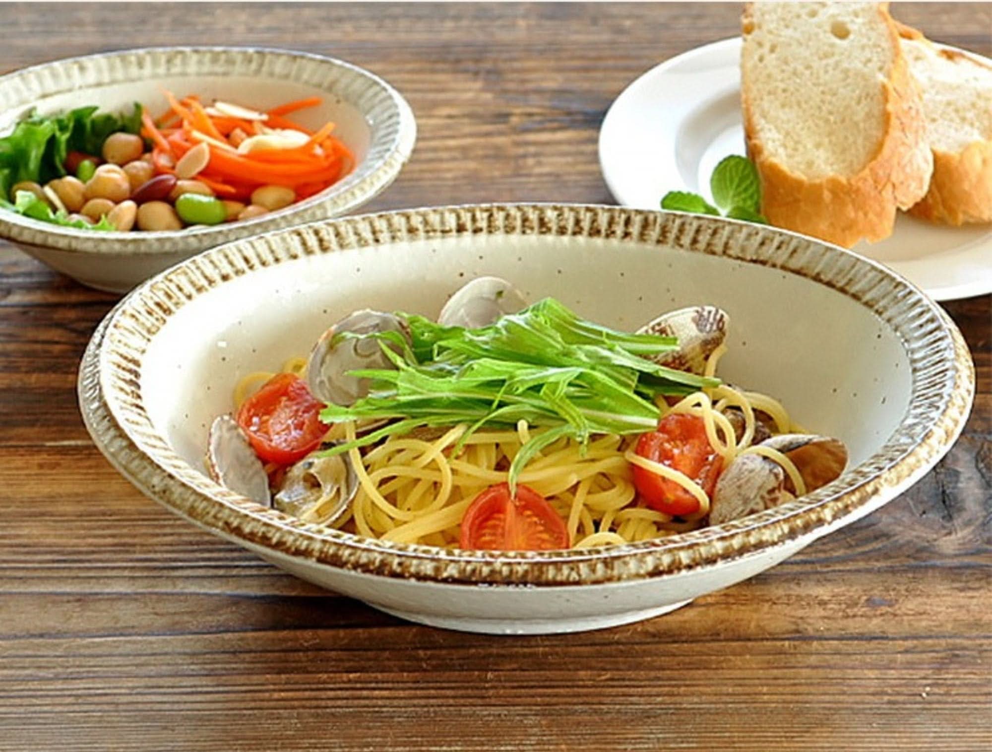 Japan imported Mino Ware Beige Dish Set with pasta, salad, and bread on rustic wood.