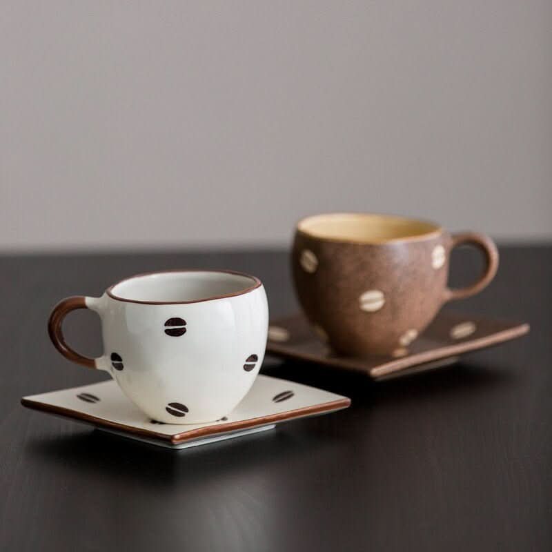 Japan Imported Mino Yaki ceramic coffee cups with coffee bean design, one white, one brown.