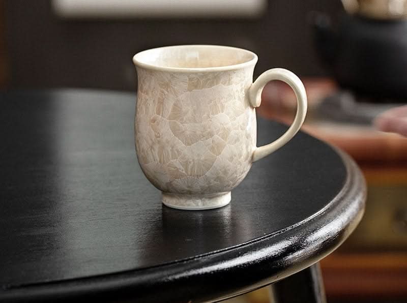 Cream crystal glaze mug on black table. Japan imported pottery, handmade ceramic water cup.
