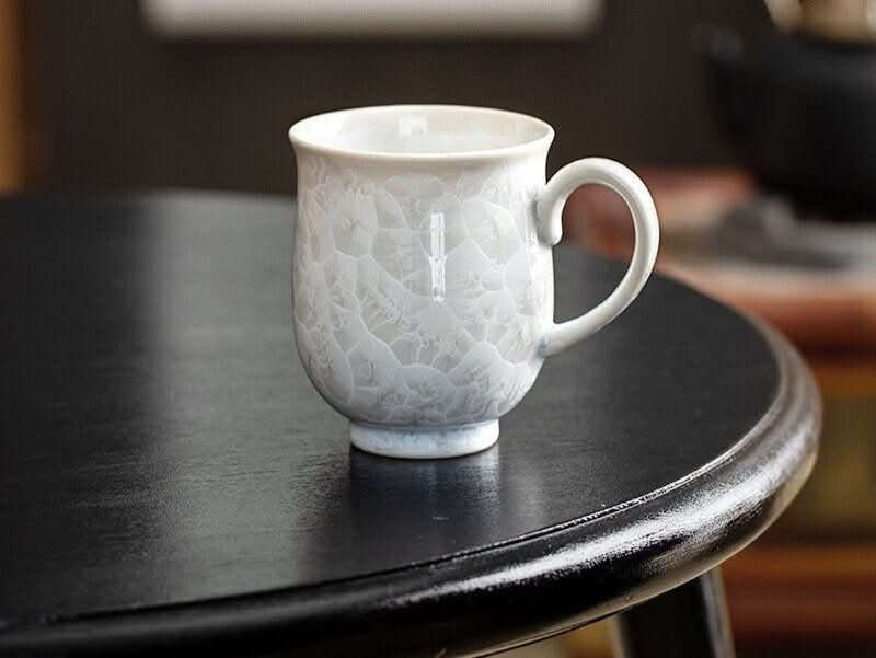 White crystal glaze mug, Japan imported pottery, handmade ceramic water cup on black table.