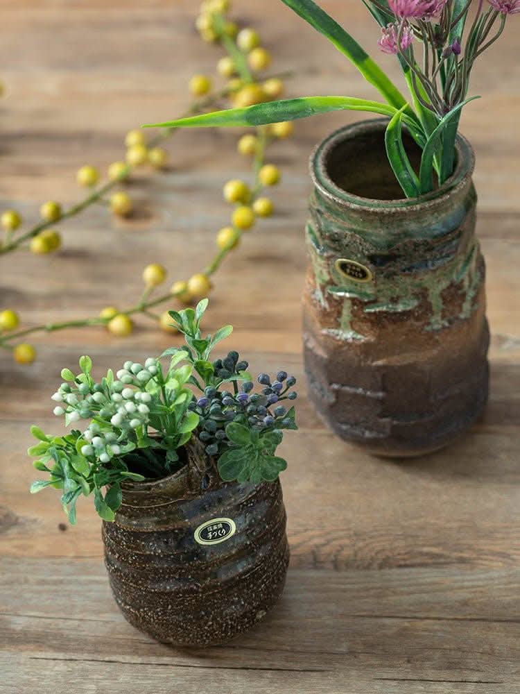 Japan imported stoneware pottery vase ornaments with green & brown glaze, holding decorative plants on wooden surface.