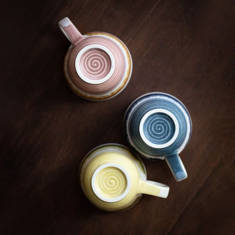 Japan Imported Stove Master Kiln Shore Cups in pink, blue, and yellow ceramic on wood.