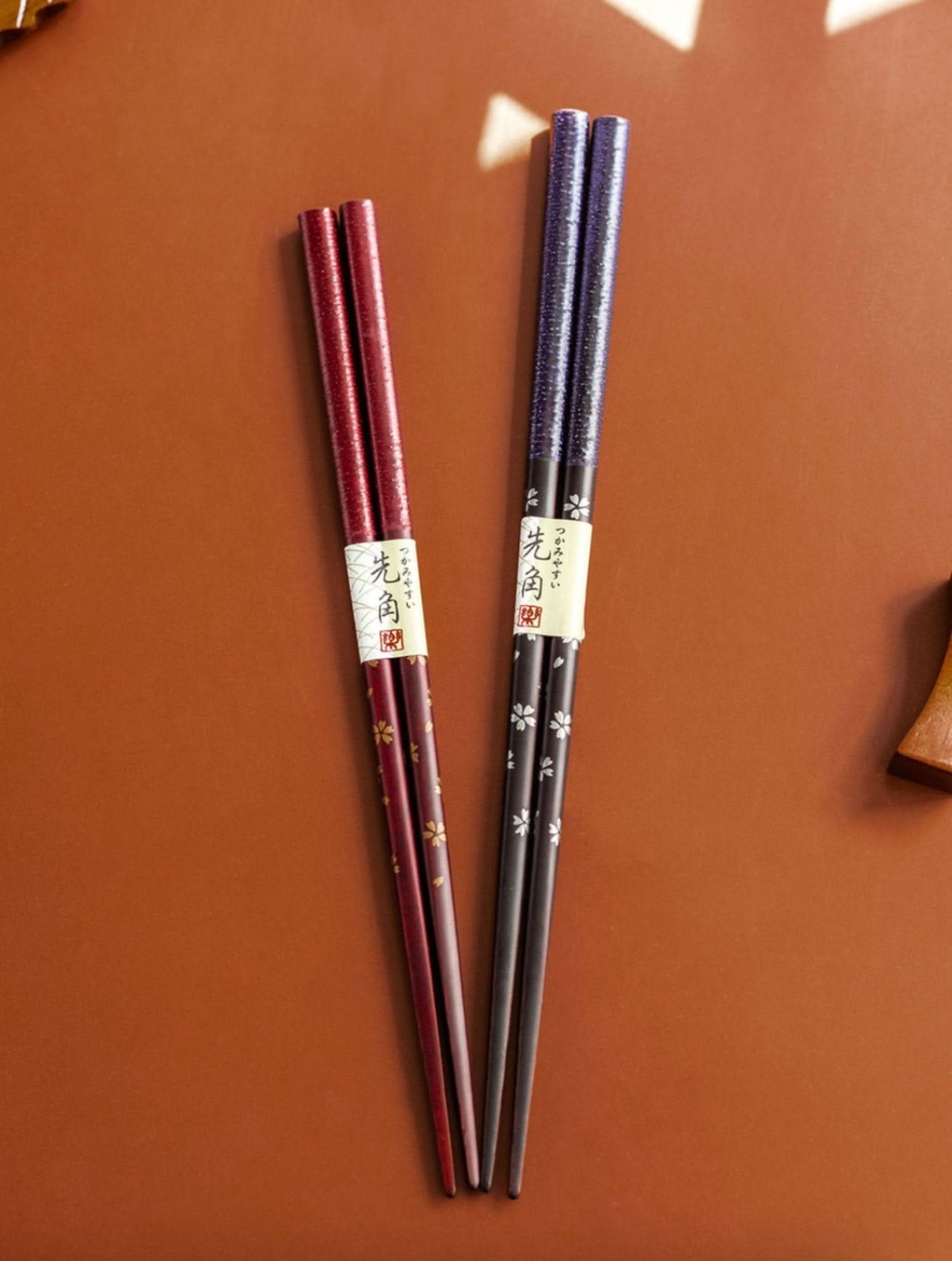 Japan Imported Sunlife Cherry Chopsticks: burgundy & navy pair on brown surface.