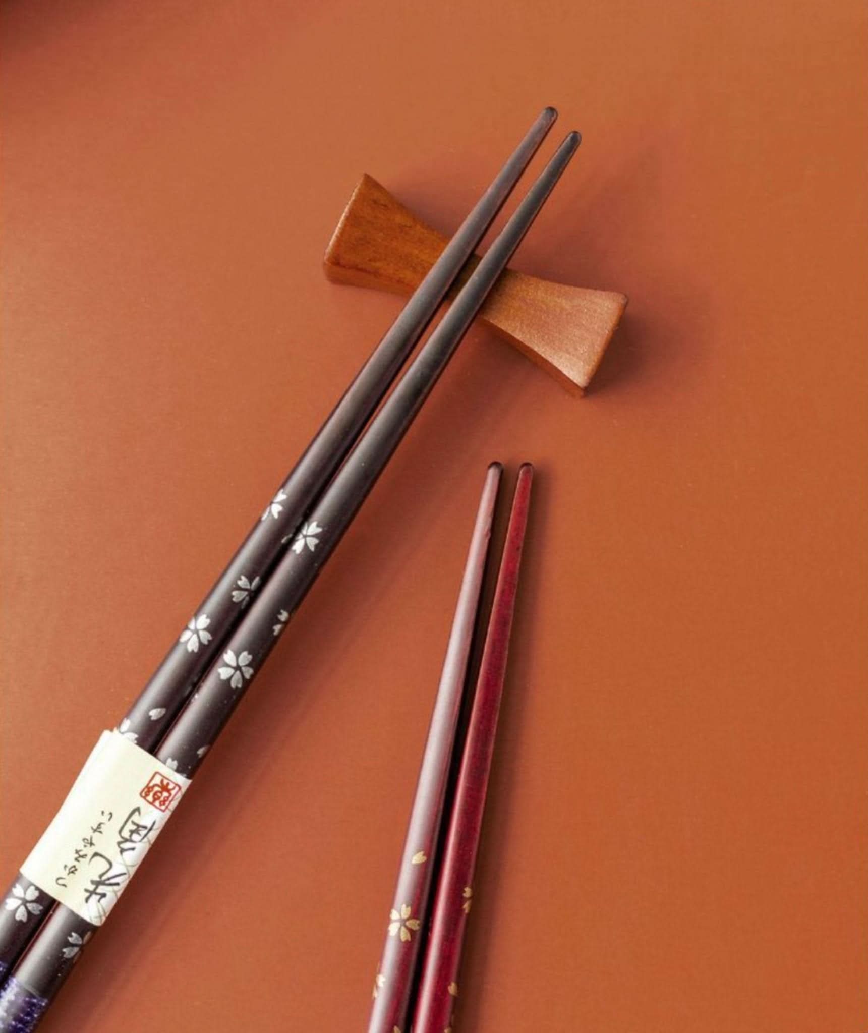 Japan Imported Sunlife solid wood chopsticks with cherry blossom design on a rustic brown surface.
