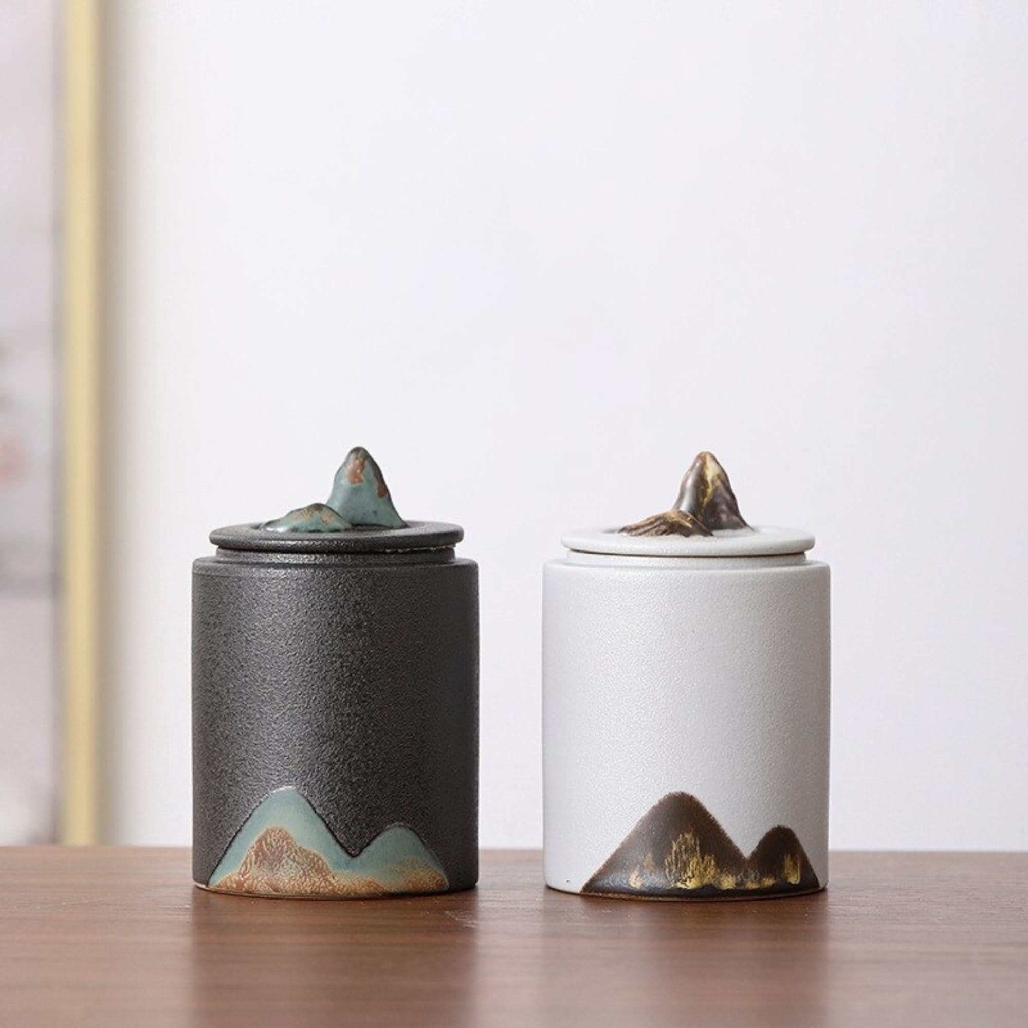 Matte finish ceramic tea canister, black and white, with mountain-shaped lid, home decor.