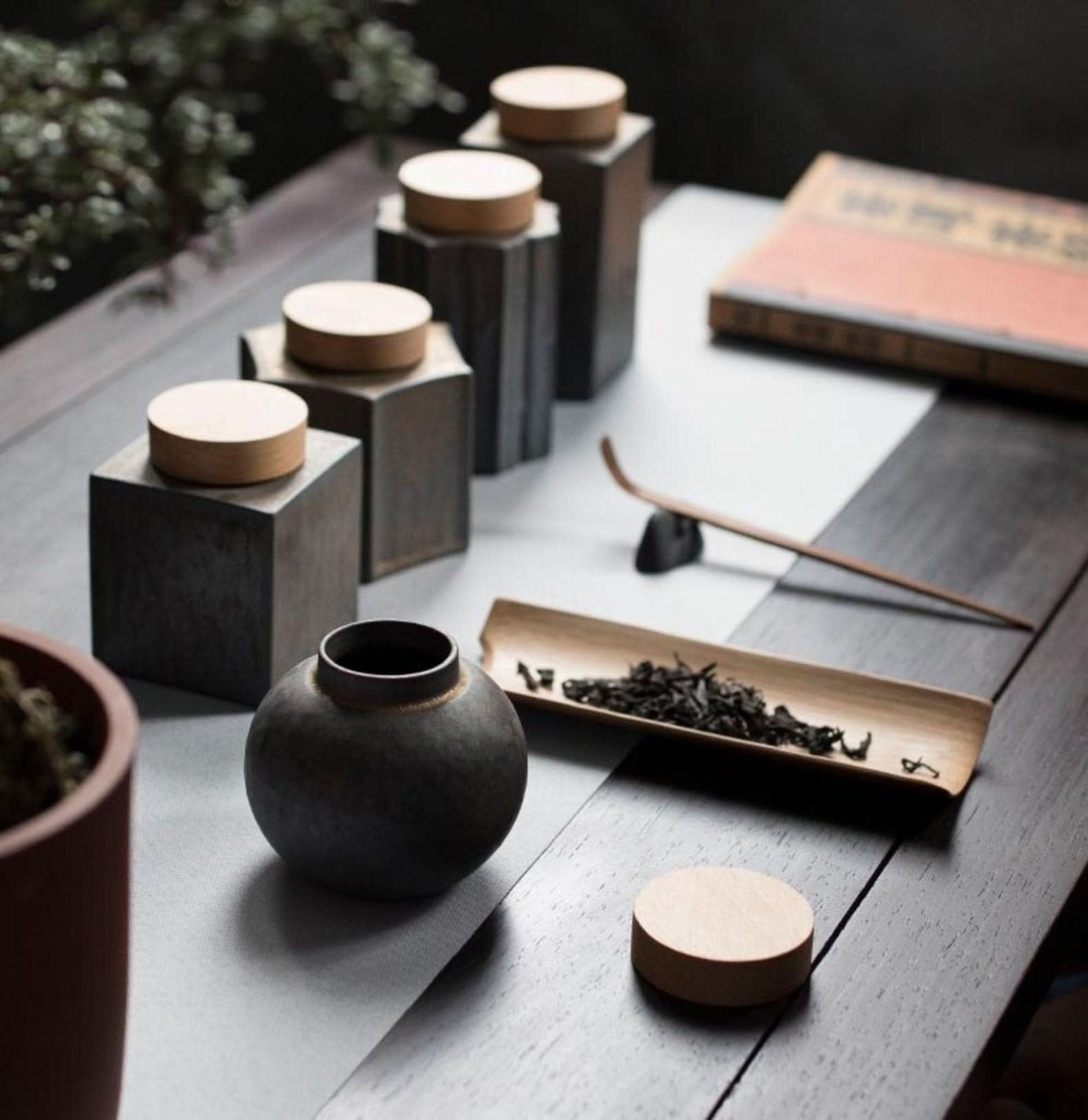 Gray ceramic tea jars with wood lids, set on a dark wooden table, home decor.