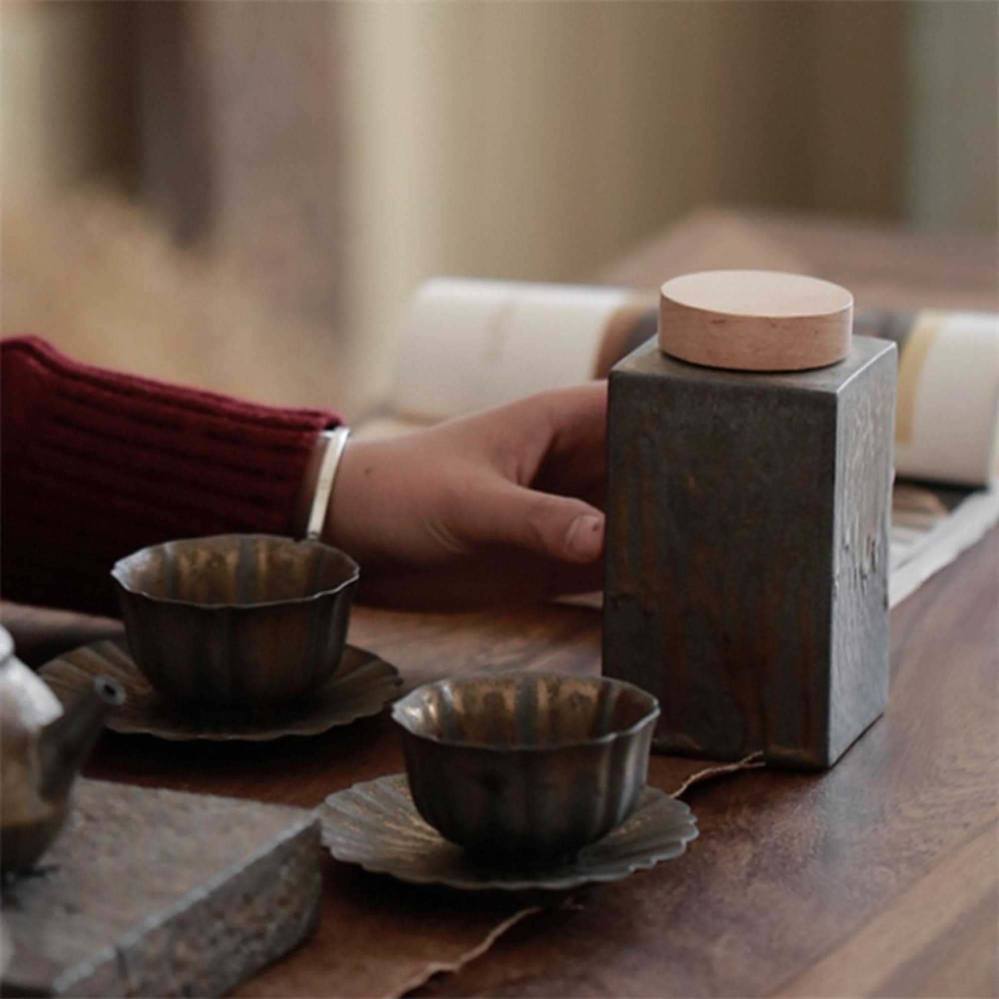 Gray ceramic tea jars with wooden lid, part of a rustic tea set display.