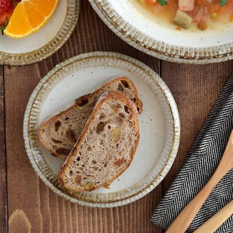 Handmade Japanese tableware set featuring bread on a rustic plate, next to soup and fruit.