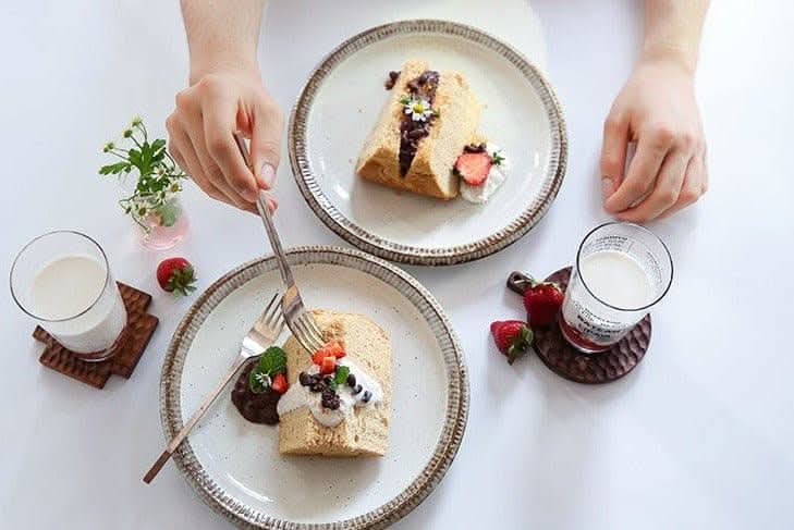 Japanese Tableware Handmade Set: Rustic plates with dessert, strawberries, and milk on white table.