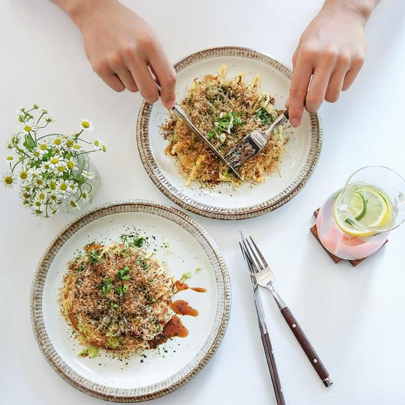Japanese Tableware Handmade Set: Two ceramic plates with food, cutlery, & flowers.