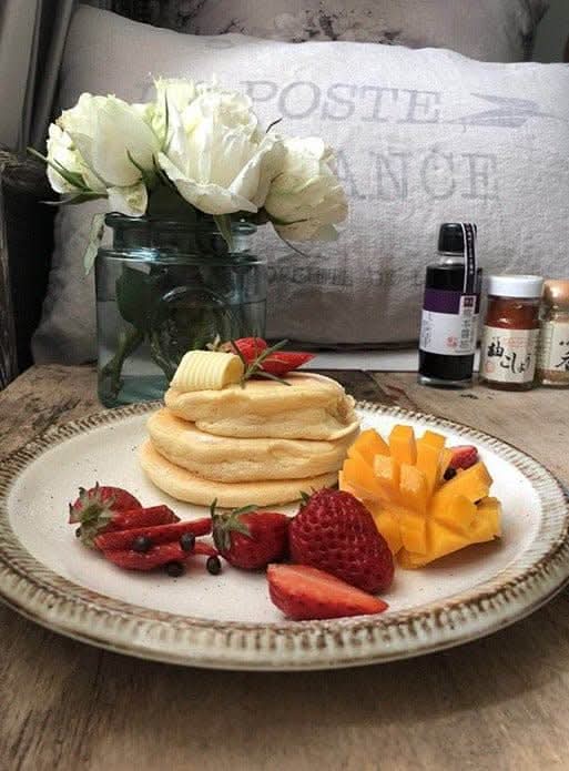 Japanese Tableware Handmade Set: Fluffy pancakes, strawberries, mango, and butter on a rustic plate with flowers.
