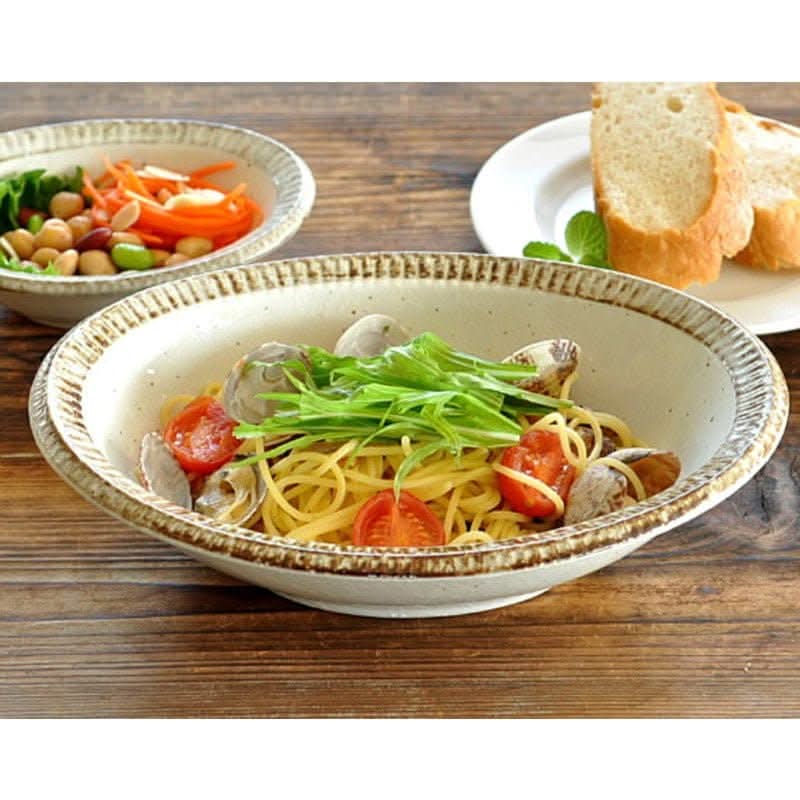 Handmade Japanese tableware set with pasta and salad. Creamy bowls with textured rims.