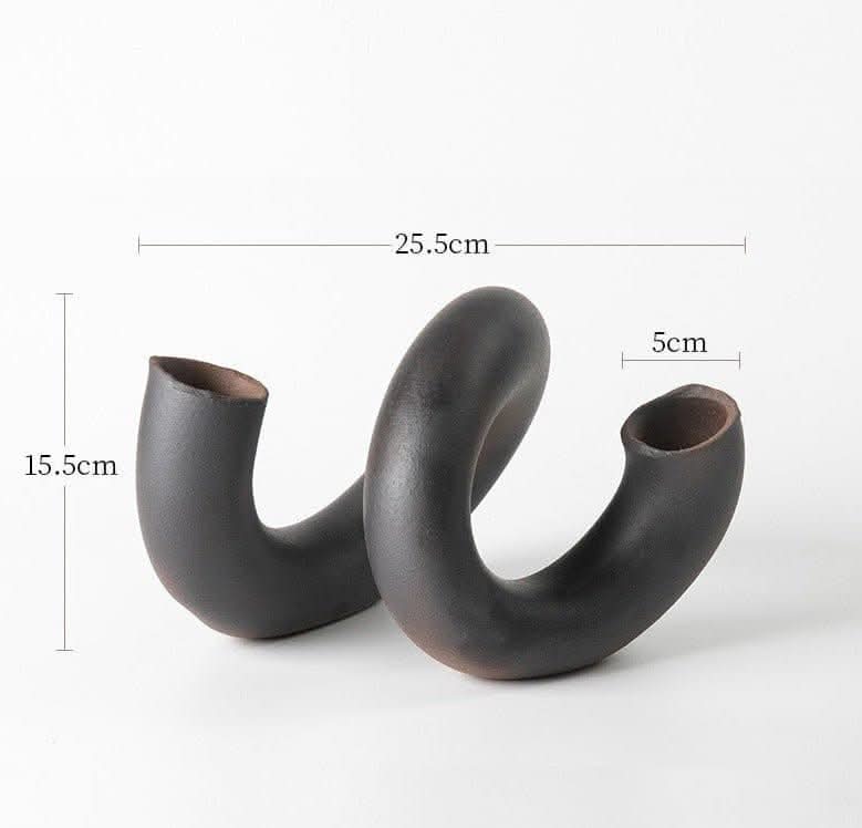 Dark brown ceramic Japanese imported irregular spiral flower vase on white background.