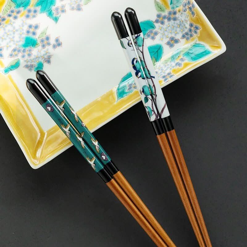 Japanese Kutani-Yaki wooden chopsticks with bird & floral designs on a decorative plate.