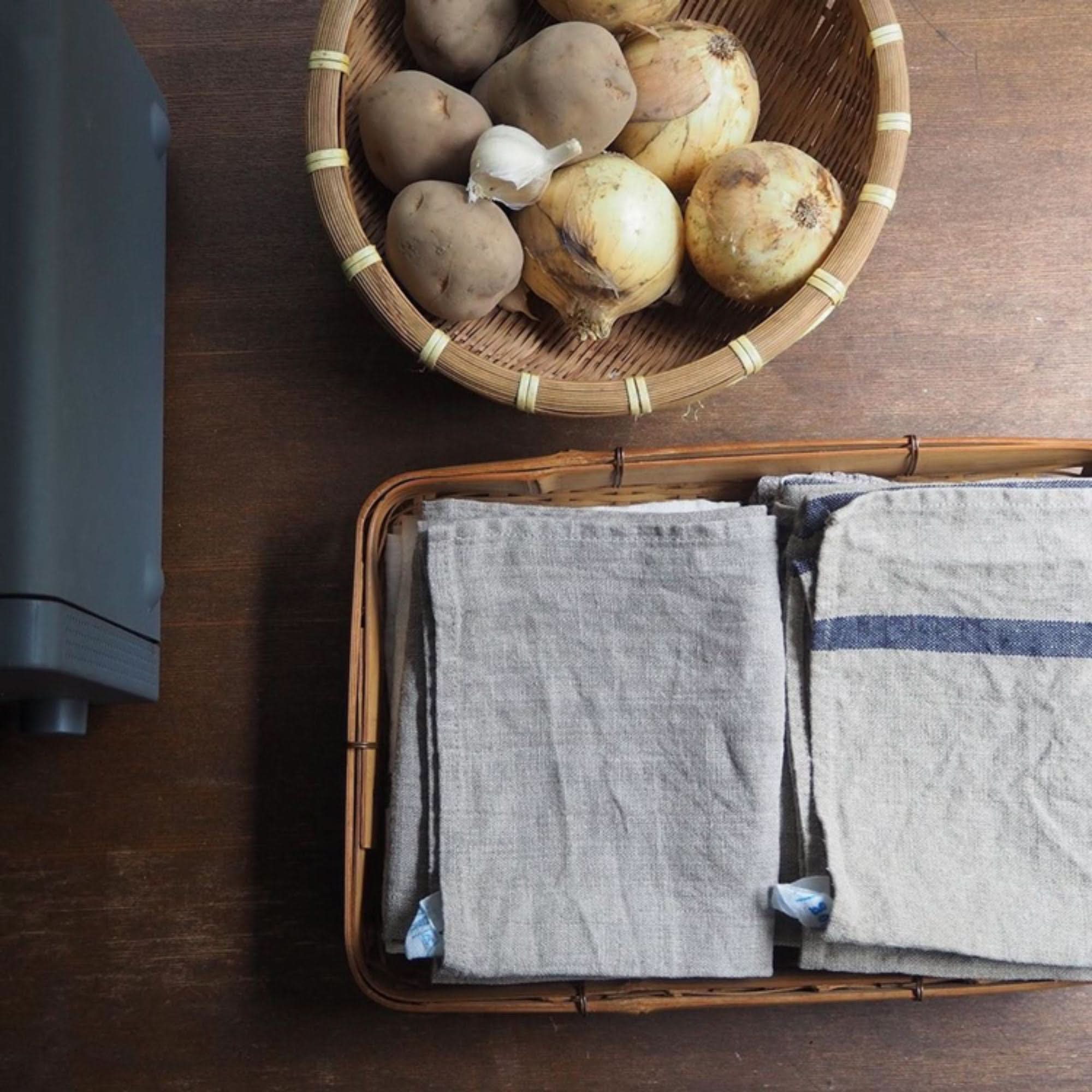 Grey and blue striped Japanese linen tea towels folded in a bamboo basket.