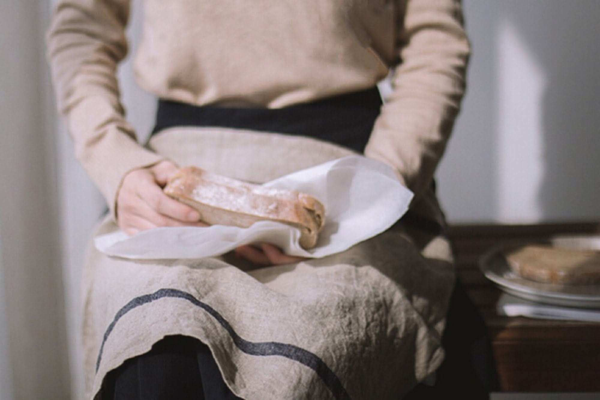 Natural linen Japanese tea towels with blue stripes, holding bread.
