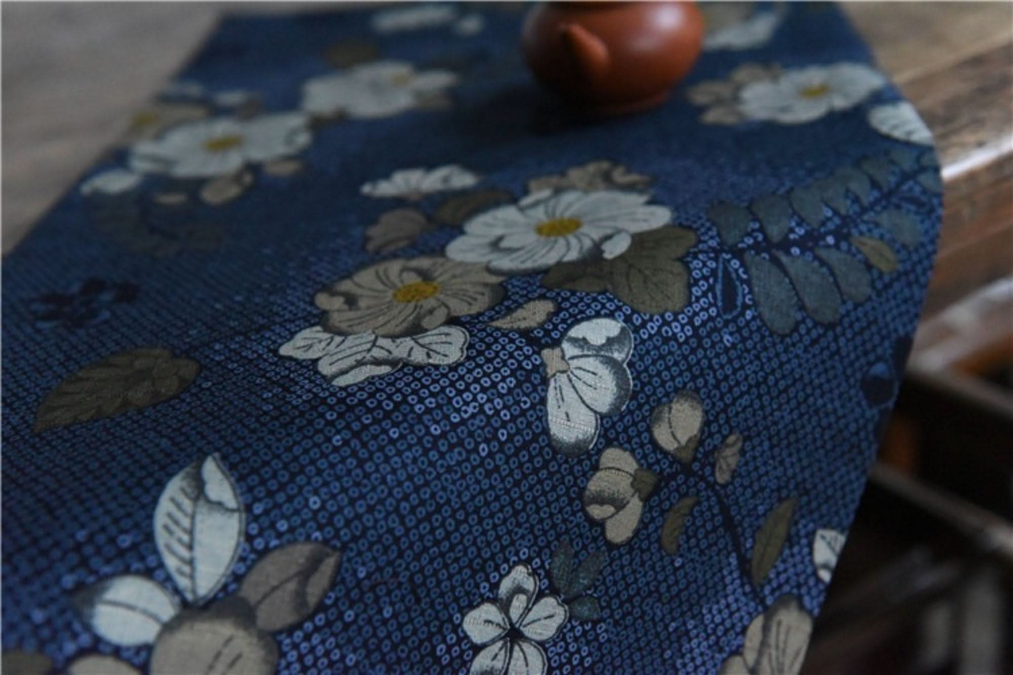 Japanese linen tea towel with floral pattern on blue, with tiny teacup.