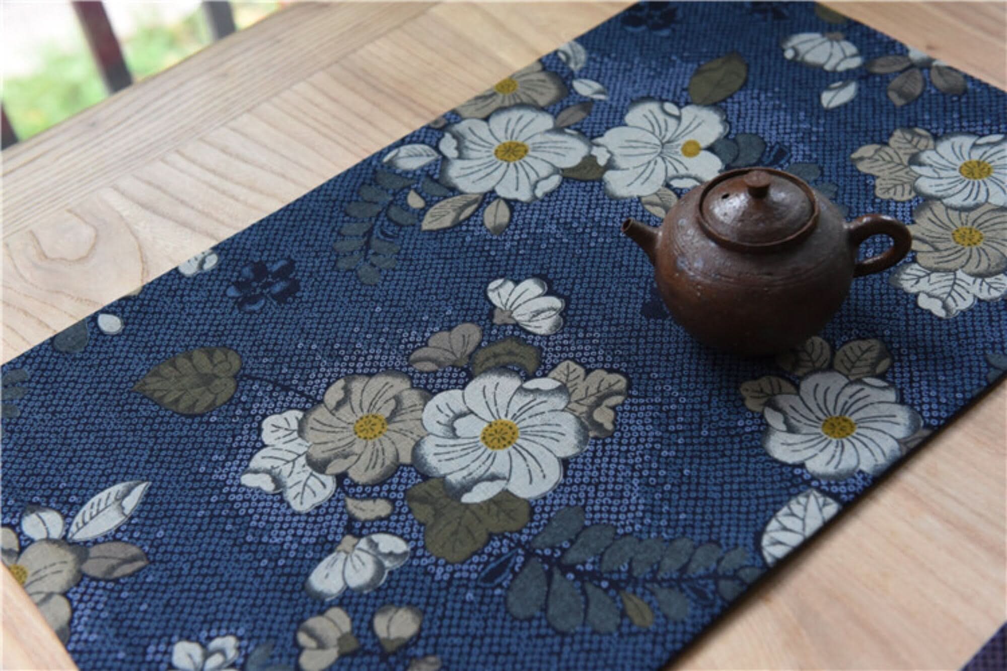 Japanese linen tea towels with floral patterns, on wooden table with tea pot.