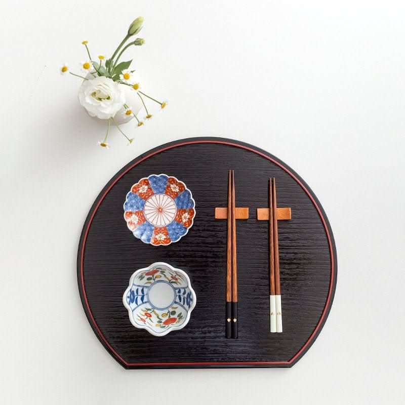 Japanese Solid Wood Peach Heart Chopsticks on a black tray with floral dishes and white flowers.