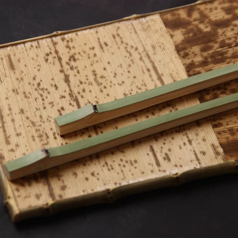 Japanese Style Bamboo Shaped Chopsticks, natural bamboo color with green tips, on bamboo mat.