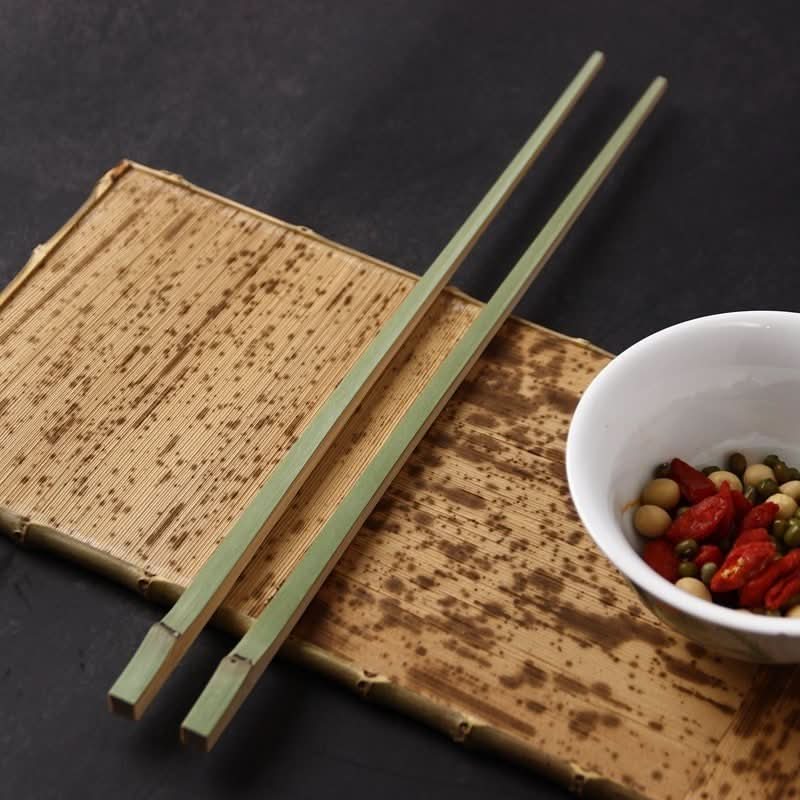 Japanese Style Bamboo Shaped Chopsticks, green & natural bamboo, on textured mat with bowl of goji berries and beans.
