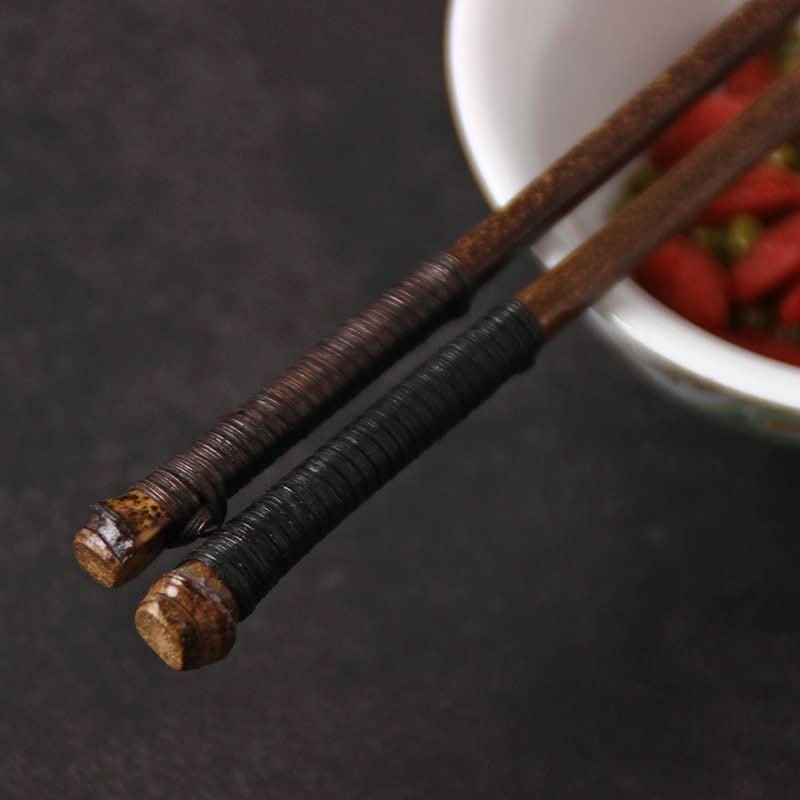 Japanese Style Bamboo Wood Chopsticks with dark brown and black wraps over a white bowl.