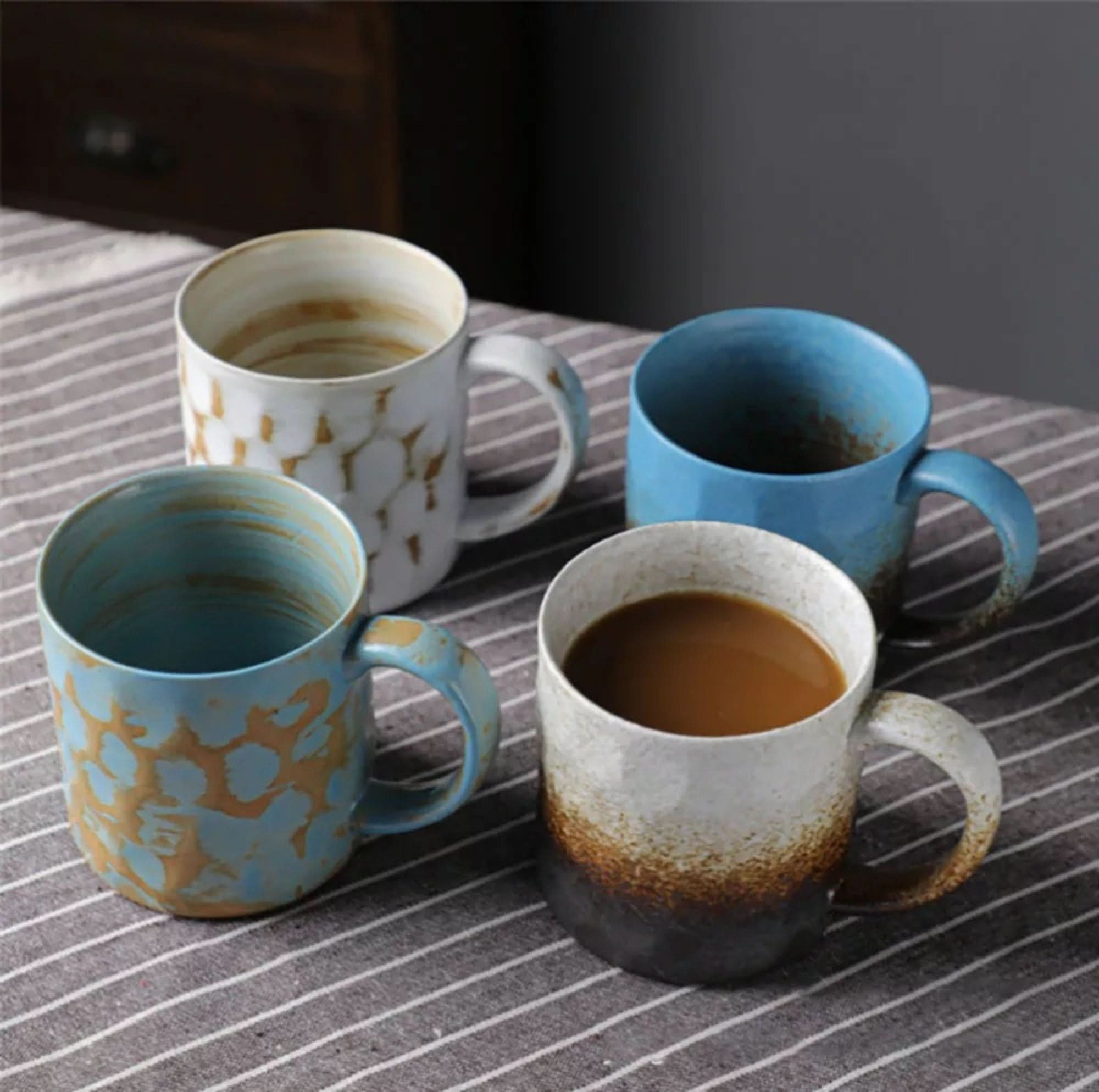 Japanese style ceramic coffee cups in blue and white with retro glaze, on striped cloth.