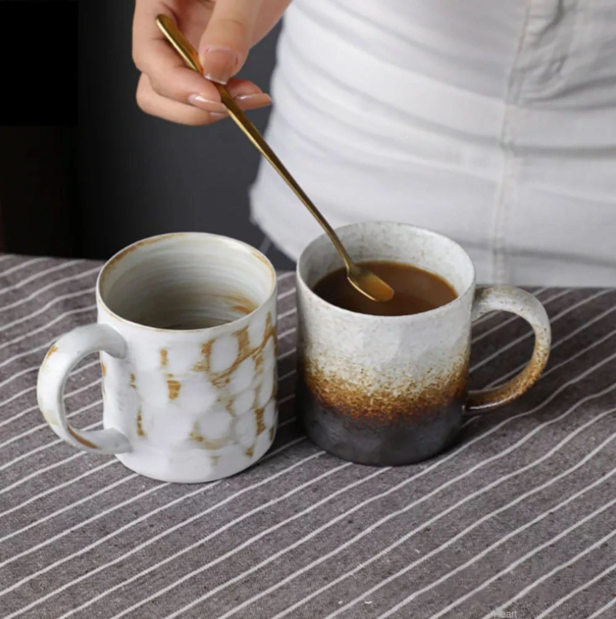Japanese style ceramic coffee cups, retro mugs with rustic finish on striped cloth.